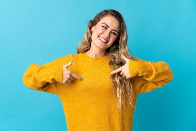 Young Brazilian woman isolated on blue wall proud and self-satisfied