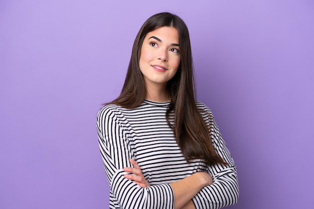 Young Brazilian woman isolated on purple background looking to the side