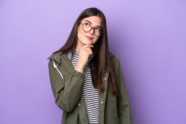 Young Brazilian woman isolated on purple background and looking up