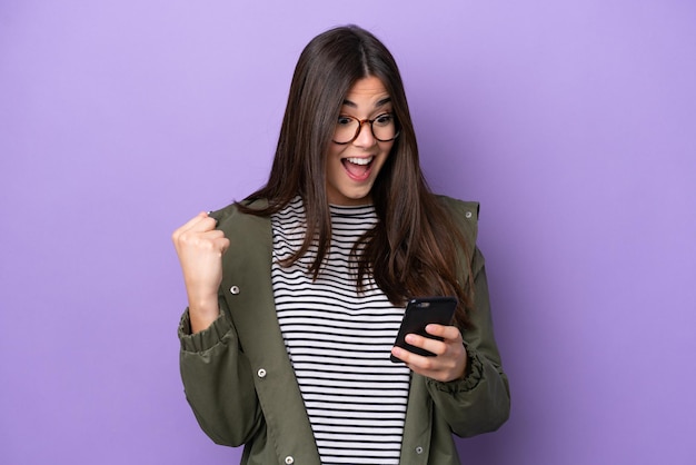 Young Brazilian woman isolated on purple background surprised and sending a message