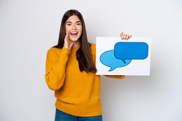 Young Brazilian woman isolated on white background holding a placard with speech bubble icon and shouting