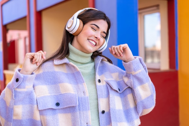 Young Brazilian woman at outdoors listening music and dancing