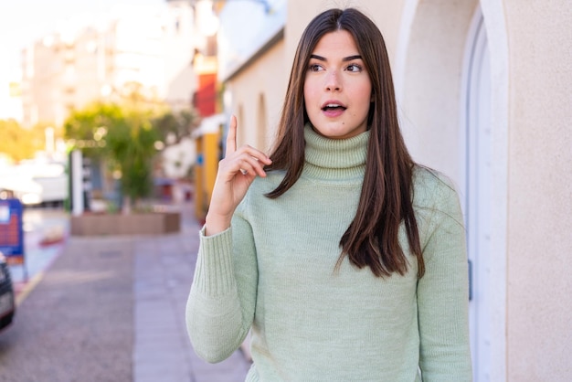 Young Brazilian woman at outdoors thinking an idea pointing the finger up