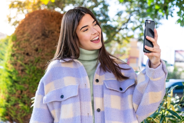 Young Brazilian woman in a park making a selfie