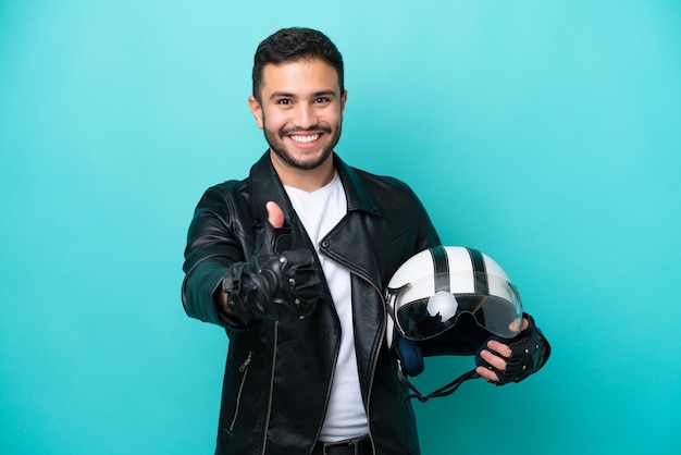 Young Brazilian woman with a motorcycle helmet isolated on blue background with thumbs up because something good has happened