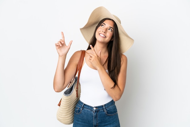 Young Brazilian woman with Pamela holding a beach bag isolated on white background pointing with the index finger a great idea