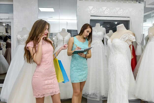 Photo young bride booking wedding dress in dealer in salon