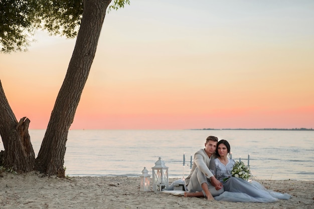 Young bride and groom near the sea on the beach at sunset