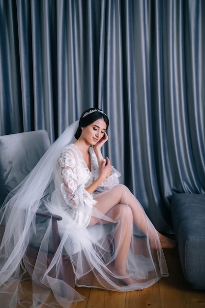 Young bride in a white robe sitting on an armchair Happy girl p