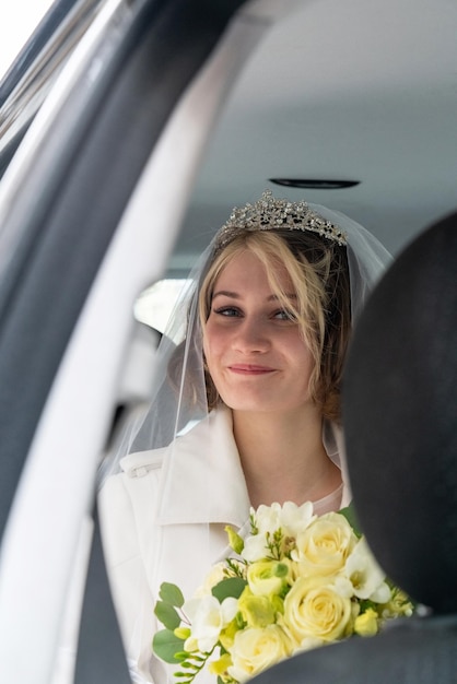 a young bride with a large bouquet of white roses sits in a car and waits for the groom Waiting for