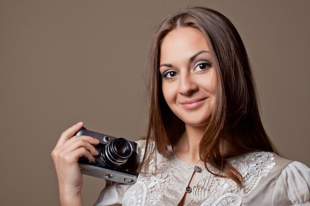 Young brown haired woman in beautiful dress holding retro camera