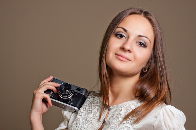 Young brown haired woman in beautiful dress holding retro camera