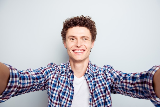 Young brunet man making selfie on grey