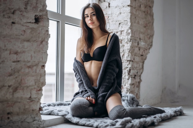 Photo young brunette in black underwear, knitted knee pads and cardigan