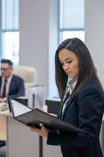 Young brunette businesswoman looking through business contract