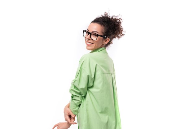 Young brunette businesswoman with curly hair dressed in a green shirt wears eyeglasses