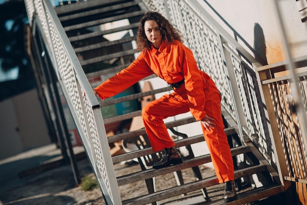 Young brunette curly woman in orange suit Female in colorful overalls portrait