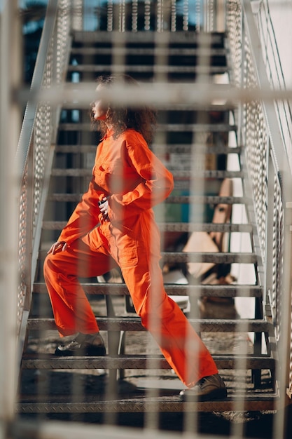 Young brunette curly woman in orange suit Female in colorful overalls portrait