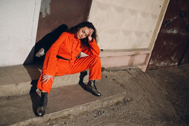 Young brunette curly woman in orange suit Female in colorful overalls portrait