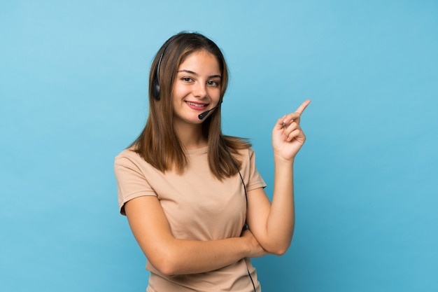 Young brunette girl over isolated blue pointing side