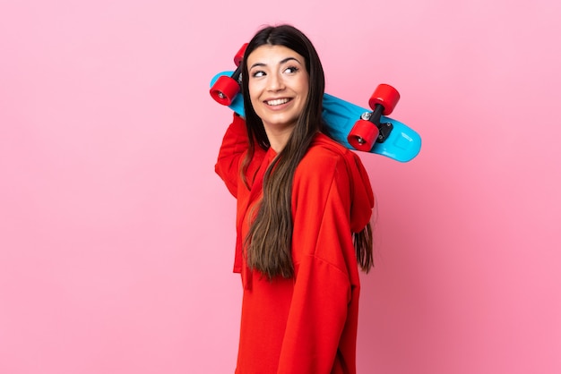 Young brunette girl over isolated pink with a skate with happy expression