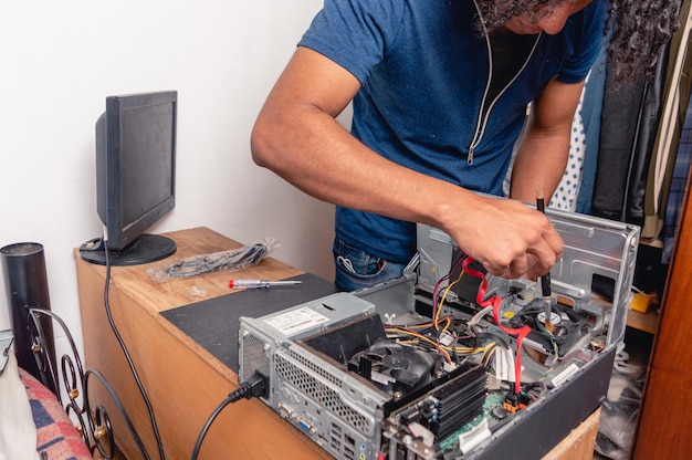 Young brunette man at home cleaning and repairing computer case