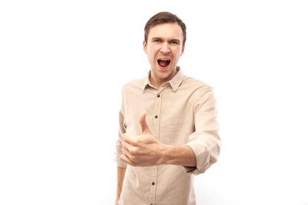 Young brunette man shows hand with thumbs up and smiles at the camera isolated on white background