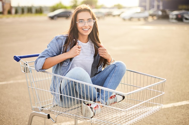 Young brunette sitting in shopping trolley