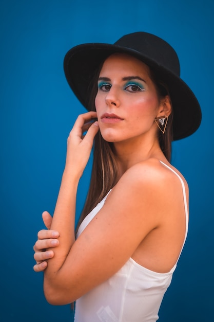 A young brunette woman in a black hat and white t-shirt