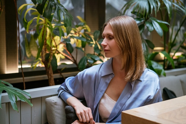 A young brunette woman in a blue shirt and white top sits semi-sideways and looks down.