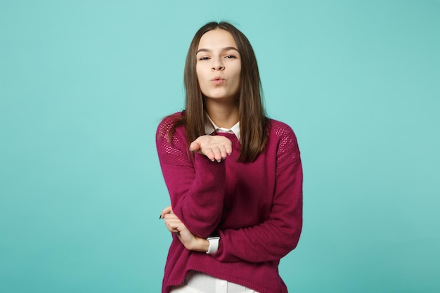 Young brunette woman girl in casual clothes posing isolated on blue wall background studio portrait. People sincere emotions lifestyle concept. Mock up copy space. Looking camera blow send air kiss.