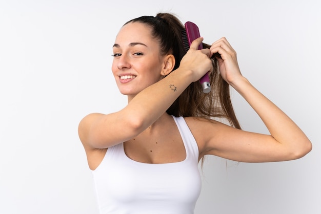 Young brunette woman over isolated white wall with hair comb