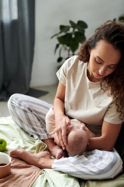 Young brunette woman looking at sleeping baby on her hands