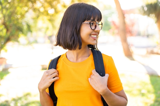 Young brunette woman at outdoors with happy expression