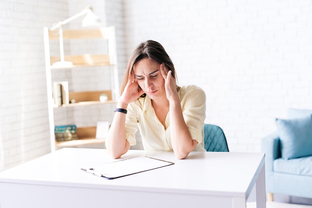 Young brunette woman suffering from headache migraine