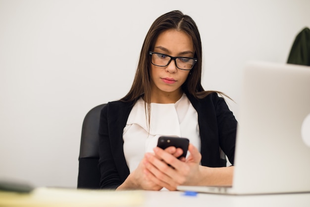 Young brunette woman using a phone at work