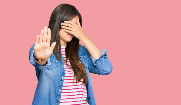 Young brunette woman wearing casual clothes covering eyes with hands and doing stop gesture with sad and fear expression embarrassed and negative concept