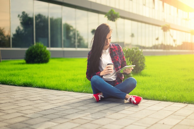 Young brunette womanwith tablet serfing in internet on grass