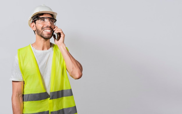 Young builder engineer in vest talking on cell phone isolated Civil engineer concept talking on cellphone isolated Smiling engineer talking on the phone isolated with copy space