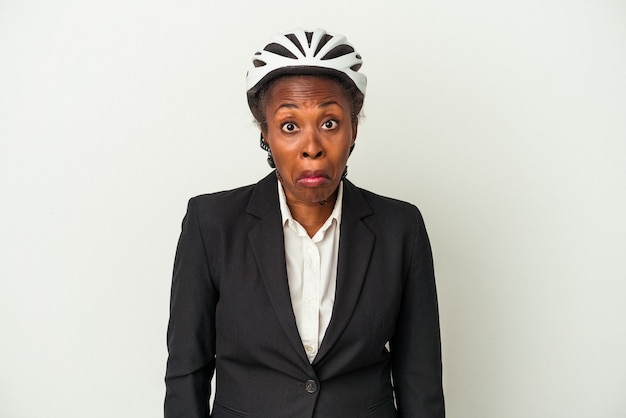 Young business african american woman wearing a bike helmet isolated on white background shrugs shoulders and open eyes confused.