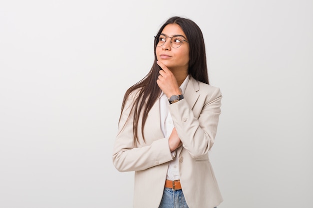 Young business arab woman isolated against a white wall looking sideways with doubtful and skeptical expression.