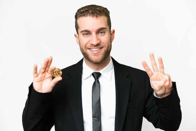 Young business blonde man holding a Bitcoin over isolated white background happy and counting three with fingers