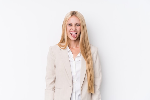 Young business blonde woman on white wall funny and friendly sticking out tongue.