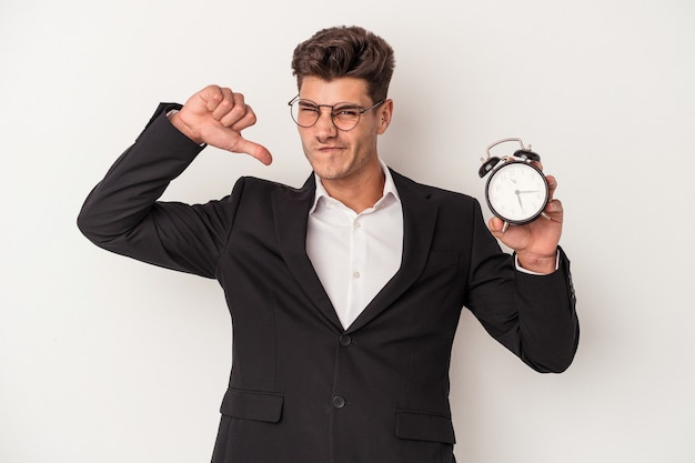 Young business caucasian man holding alarm clock isolated on white background feels proud and self confident, example to follow.