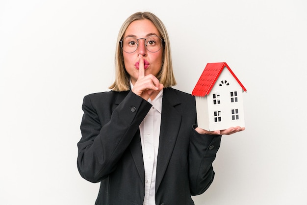 Young business caucasian woman holding a toy house isolated on white background keeping a secret or asking for silence