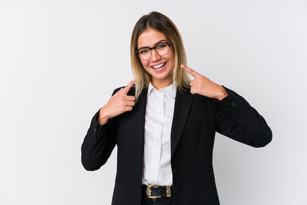 Young business caucasian woman smiles, pointing fingers at mouth.