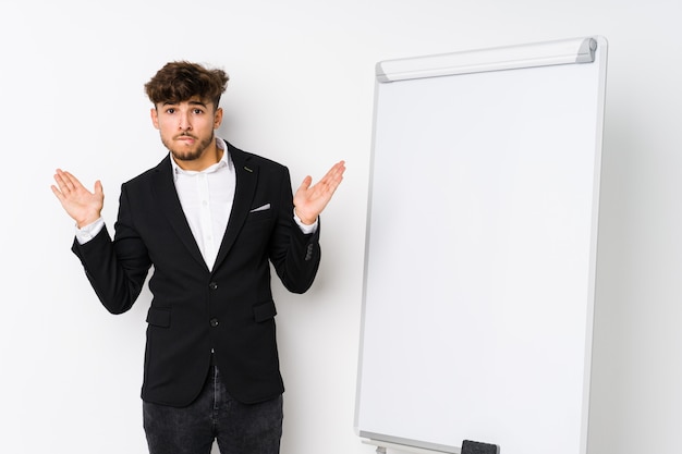 Young business coaching arabian man confused and doubtful shrugging shoulders to hold a copy space.