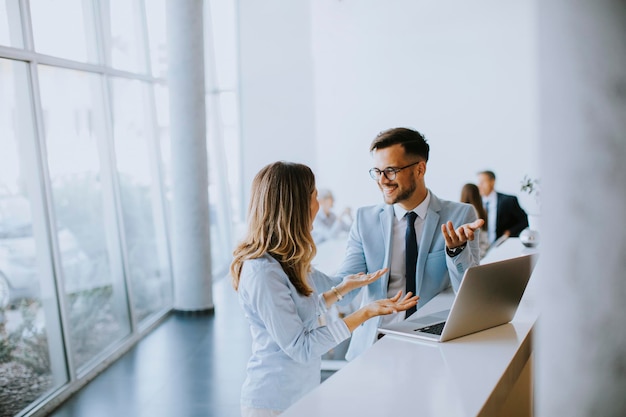 Young business couple working and discussing by laptop in the office in front of their team