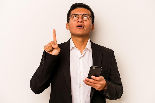 Young business hispanic man holding mobile phone isolated on white background pointing upside with opened mouth