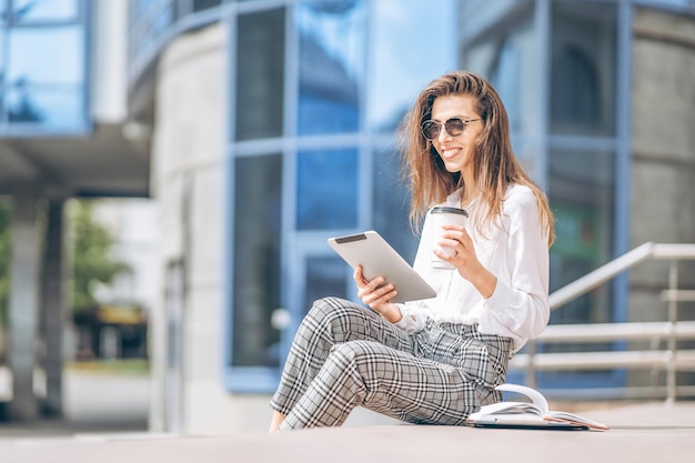 Young business lady working on the tablet outdoors near business center